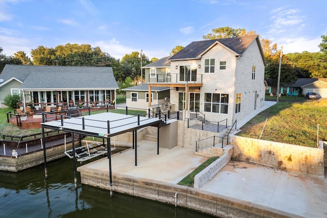 back of property featuring a water view, a patio, and a balcony