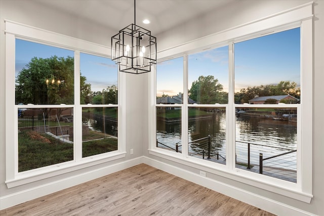 unfurnished sunroom with a water view, an inviting chandelier, and a healthy amount of sunlight