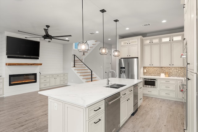 kitchen featuring an island with sink, light hardwood / wood-style floors, appliances with stainless steel finishes, and sink