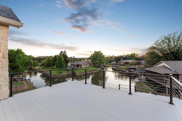 deck at dusk featuring a water view