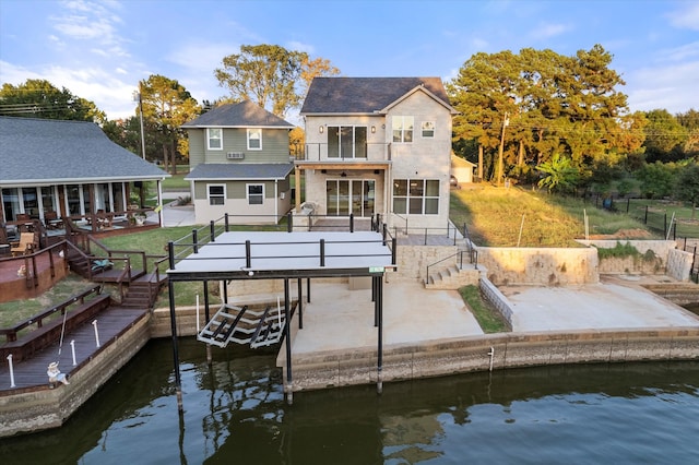 view of dock with a deck with water view, a lawn, and a patio area