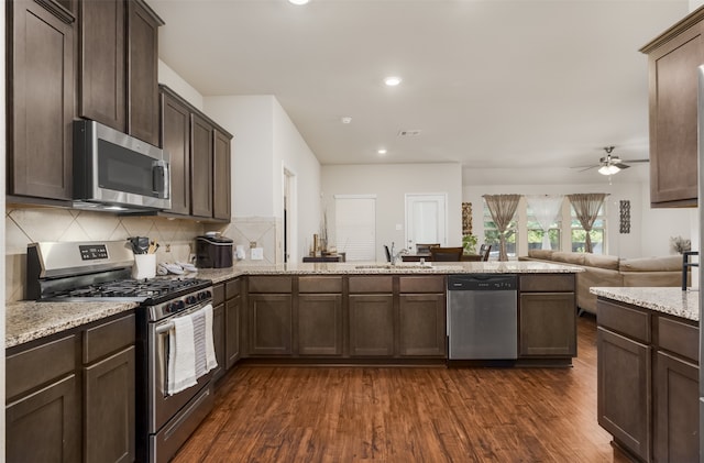 kitchen featuring ceiling fan, sink, light stone counters, stainless steel appliances, and dark hardwood / wood-style floors