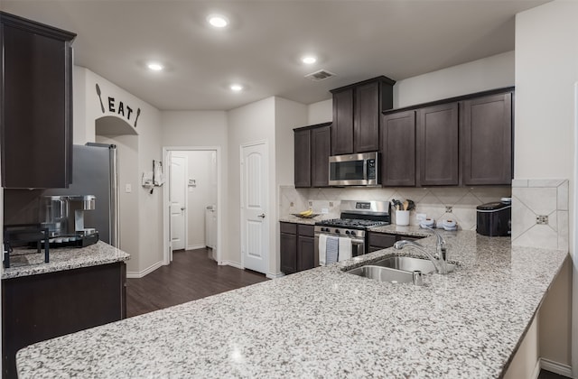 kitchen featuring stainless steel appliances, light stone countertops, dark hardwood / wood-style floors, and sink