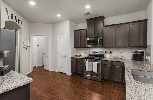 kitchen with light stone countertops, appliances with stainless steel finishes, and dark hardwood / wood-style floors