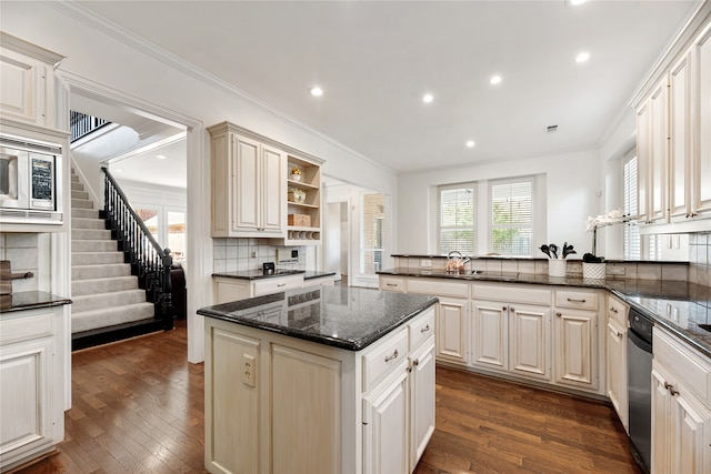 kitchen with ornamental molding, kitchen peninsula, backsplash, dark hardwood / wood-style floors, and dark stone counters