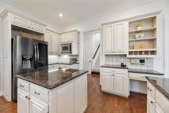 kitchen featuring tasteful backsplash, crown molding, dark wood-type flooring, dark stone countertops, and appliances with stainless steel finishes