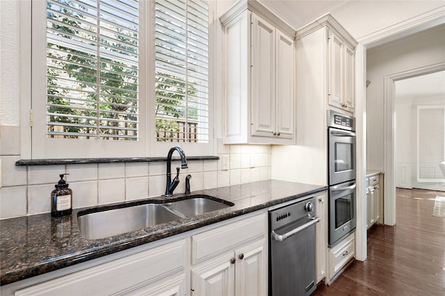 kitchen featuring white cabinets, sink, dark wood-type flooring, stainless steel double oven, and dark stone counters