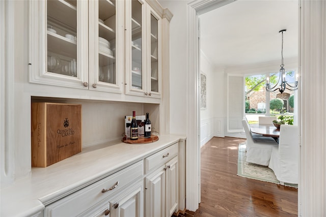 bar with a notable chandelier, decorative light fixtures, white cabinetry, and dark hardwood / wood-style floors