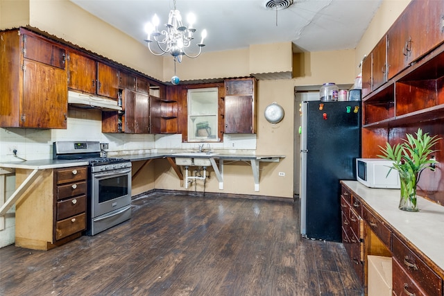 kitchen with dark hardwood / wood-style floors, stainless steel appliances, tasteful backsplash, pendant lighting, and an inviting chandelier