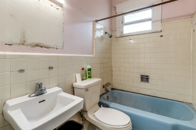 full bathroom with sink, tile walls, tiled shower / bath combo, and toilet