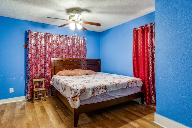 bedroom featuring hardwood / wood-style flooring, ceiling fan, and a textured ceiling