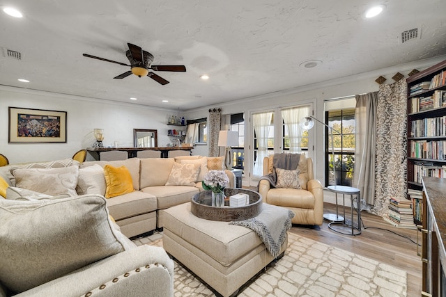 living room featuring crown molding, ceiling fan, and light hardwood / wood-style flooring