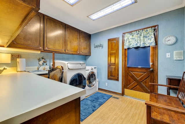 laundry area with ornamental molding, cabinets, light wood-type flooring, and independent washer and dryer