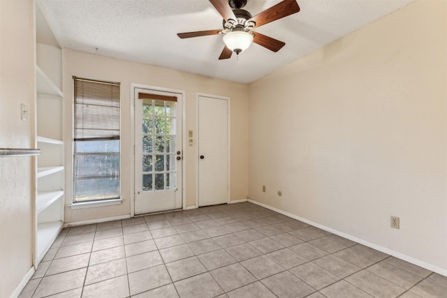 empty room with ceiling fan, light tile patterned floors, and a textured ceiling