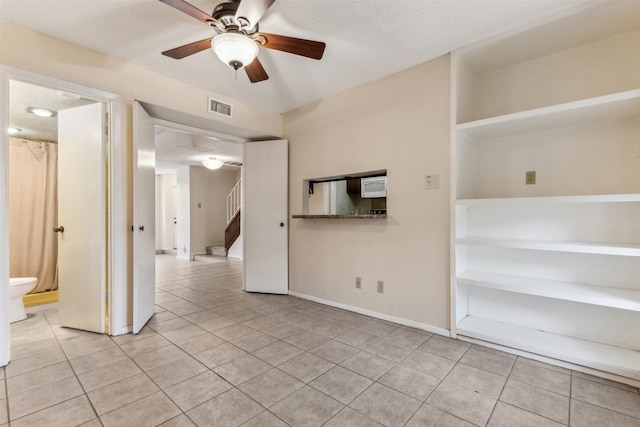 tiled empty room featuring ceiling fan