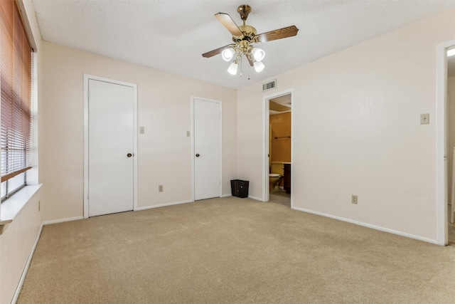 unfurnished bedroom featuring light carpet, connected bathroom, and ceiling fan