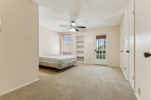 unfurnished bedroom with a textured ceiling, light colored carpet, and ceiling fan