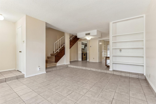 unfurnished living room featuring light tile patterned floors and a textured ceiling