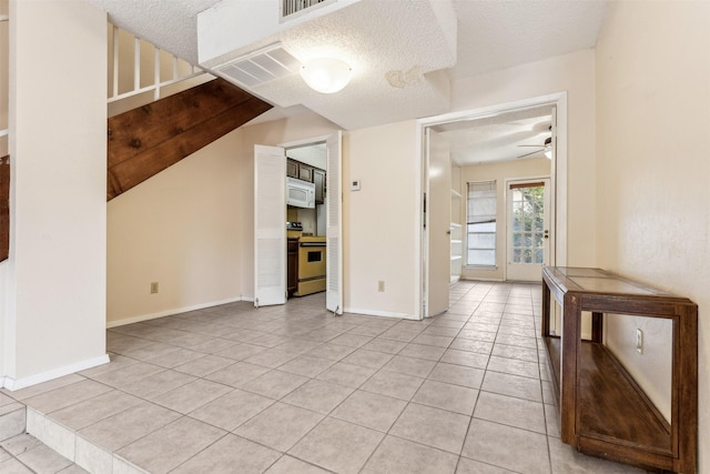 unfurnished living room featuring ceiling fan, light tile patterned floors, and a textured ceiling