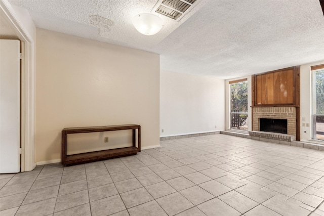 unfurnished living room featuring a fireplace, a textured ceiling, and light tile patterned floors