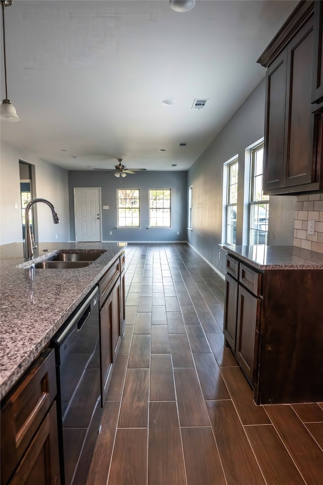 kitchen featuring dark stone countertops, a wealth of natural light, sink, and dishwasher