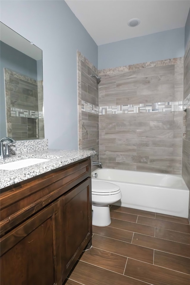 full bathroom with tiled shower / bath, vanity, and toilet