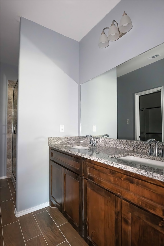 bathroom featuring a shower with door and vanity