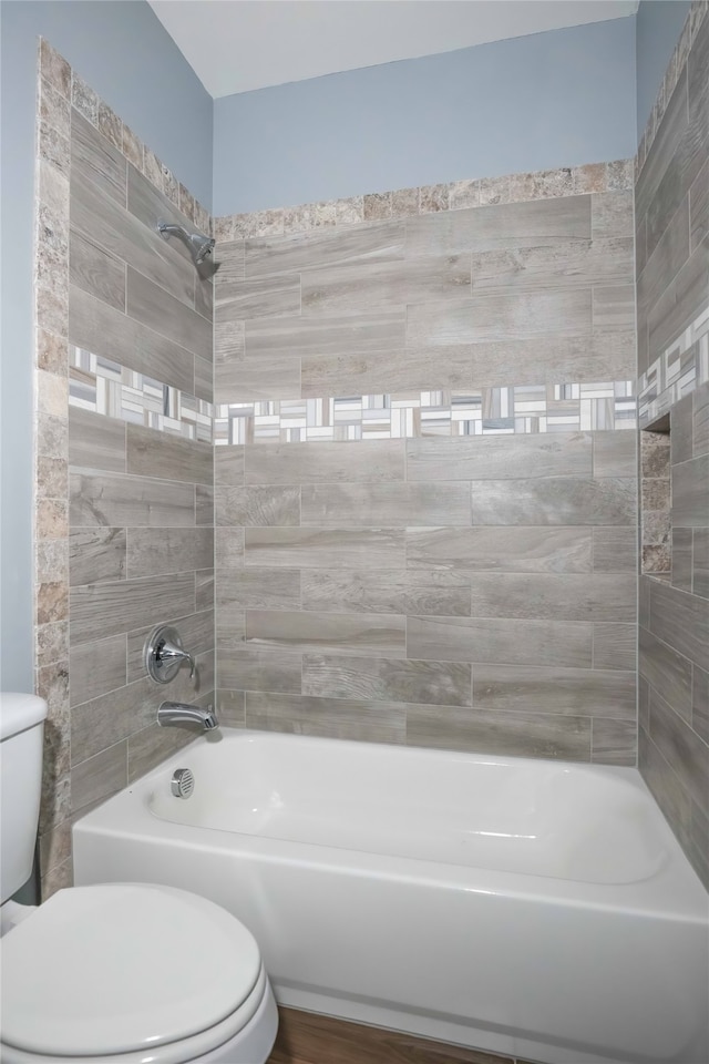 bathroom featuring tiled shower / bath combo and toilet