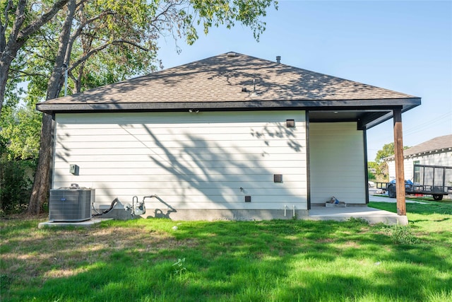 rear view of house featuring central AC and a lawn