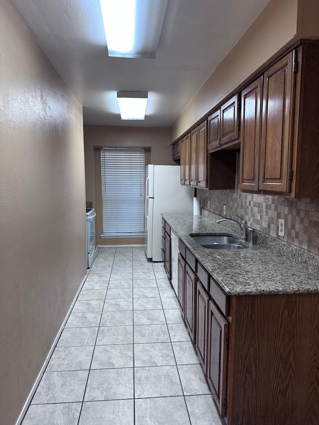 kitchen with light tile patterned flooring, tasteful backsplash, stove, dark brown cabinetry, and sink