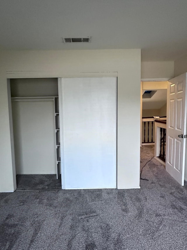 unfurnished bedroom with a closet and dark carpet