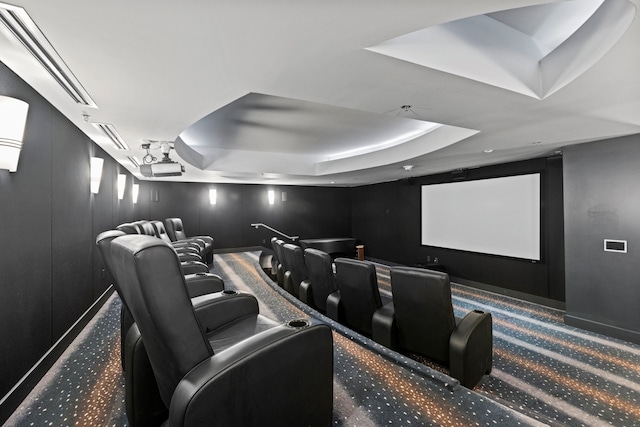 home theater room featuring a tray ceiling and carpet flooring