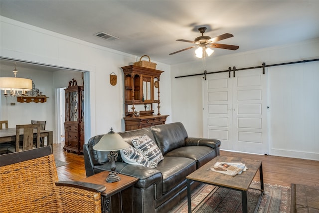 living room with ceiling fan, hardwood / wood-style flooring, crown molding, and a barn door