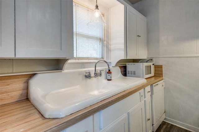 kitchen with hanging light fixtures, sink, white appliances, white cabinetry, and light hardwood / wood-style floors