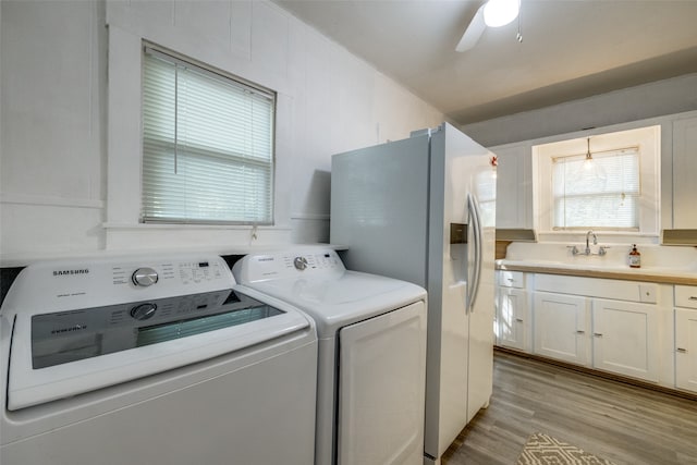 clothes washing area featuring ceiling fan, sink, light wood-type flooring, and washer and dryer