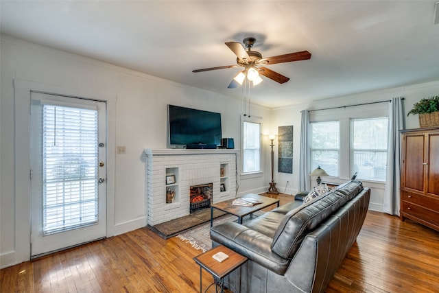 living room with ornamental molding, hardwood / wood-style flooring, a fireplace, and ceiling fan