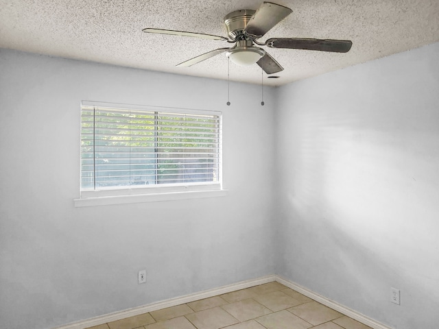 empty room featuring ceiling fan, a textured ceiling, and light tile patterned floors