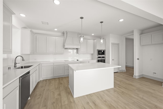 kitchen with a kitchen island, light hardwood / wood-style flooring, sink, white cabinetry, and appliances with stainless steel finishes