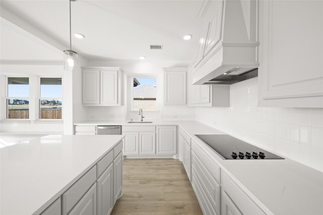 kitchen with custom exhaust hood, white cabinets, black electric cooktop, light hardwood / wood-style floors, and sink