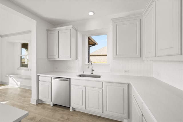 kitchen featuring sink, dishwasher, light wood-type flooring, white cabinets, and decorative backsplash