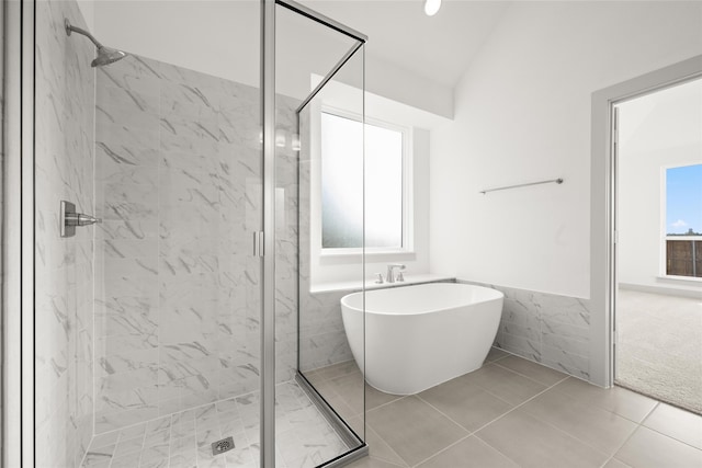 bathroom featuring tile patterned floors, lofted ceiling, separate shower and tub, and tile walls