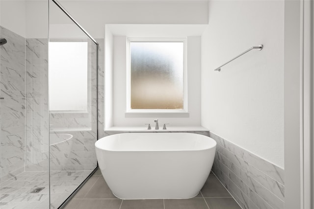 bathroom with tile patterned flooring, tile walls, and separate shower and tub