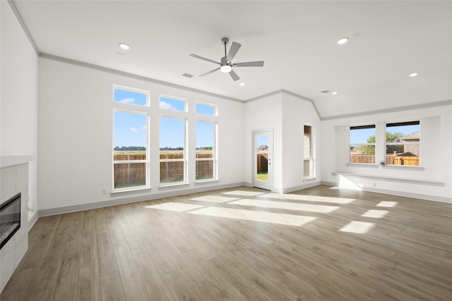 unfurnished living room with a tiled fireplace, ornamental molding, light wood-type flooring, and ceiling fan