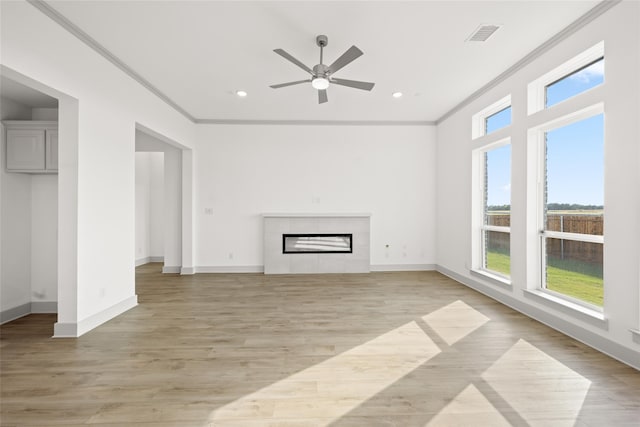 unfurnished living room featuring ornamental molding, light hardwood / wood-style flooring, a tiled fireplace, and ceiling fan