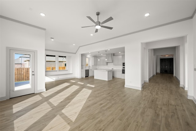 unfurnished living room featuring crown molding, light hardwood / wood-style flooring, vaulted ceiling, and ceiling fan