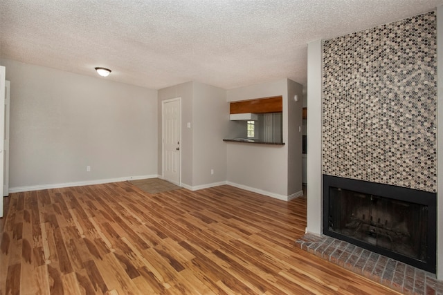 unfurnished living room with a fireplace, hardwood / wood-style flooring, and a textured ceiling