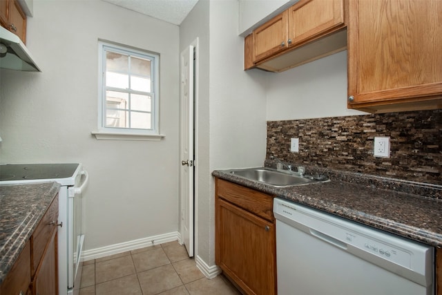 kitchen with tasteful backsplash, white appliances, sink, dark stone counters, and light tile patterned floors