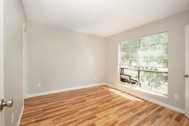 unfurnished room featuring light wood-type flooring and a textured ceiling