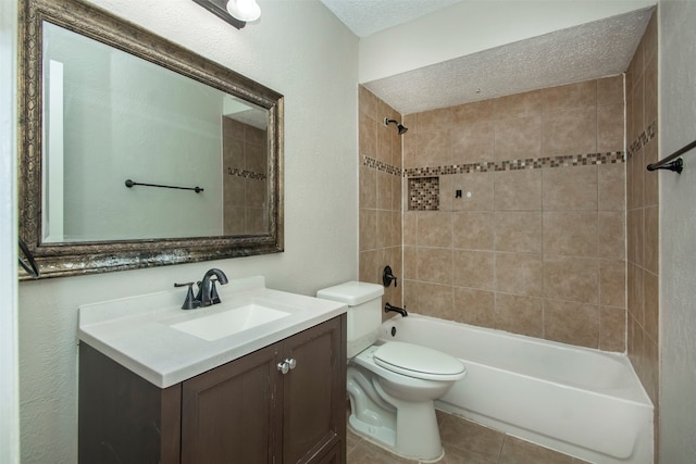 full bathroom with a textured ceiling, tiled shower / bath, vanity, and toilet