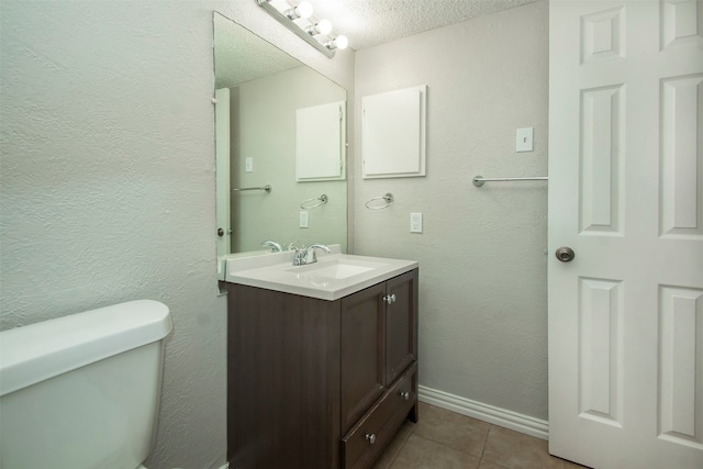 bathroom with tile patterned floors, toilet, vanity, and a textured ceiling